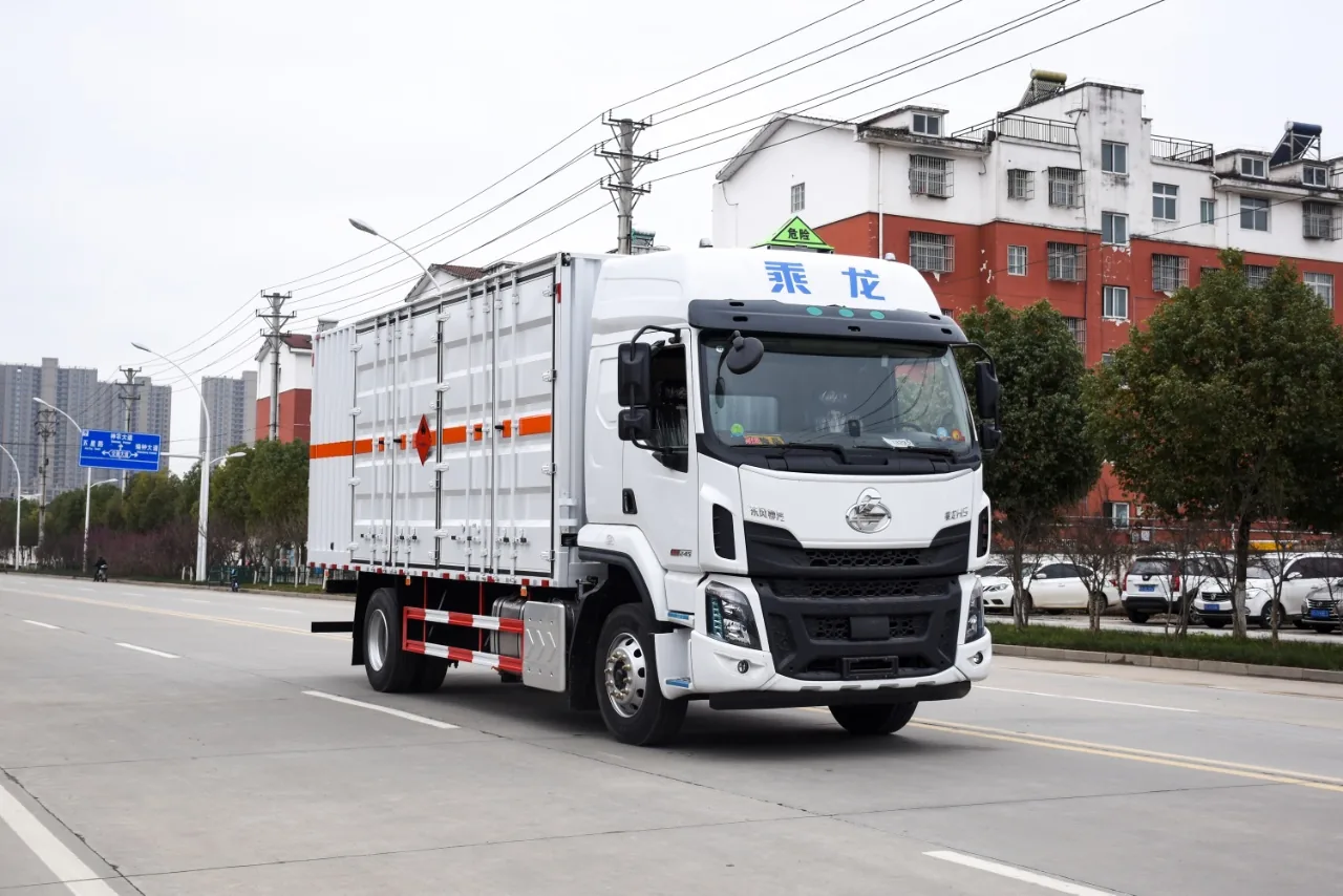 乘龙H5危化品厢式运输车 白厢款右前45度行驶实拍：高顶双卧驾驶室（乘龙字标）+ 白色瓦楞厢体 + 橙色反光带 + 危险品顶灯