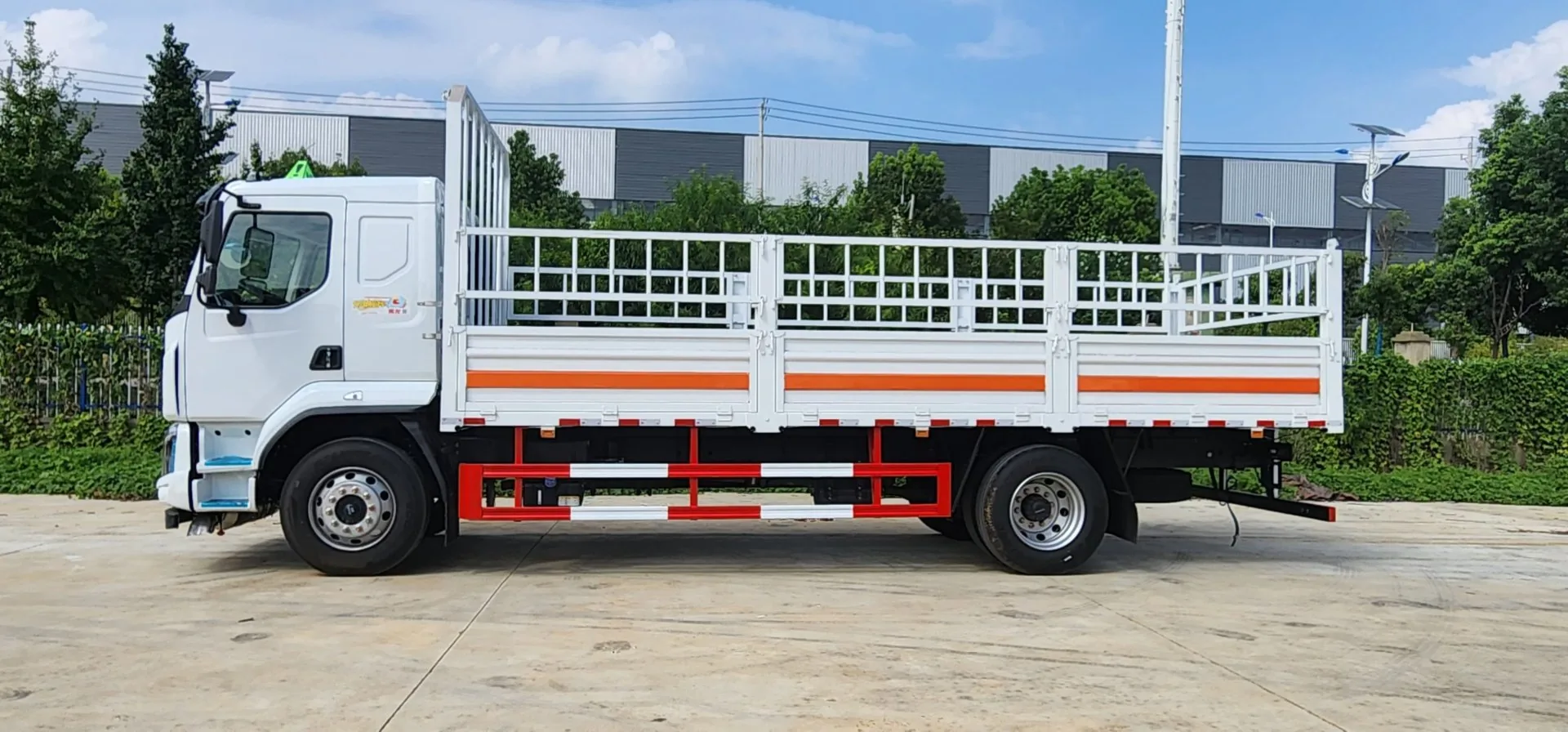东风柳汽乘龙M3危险品仓栅运输车 左侧正侧面实拍：白色栏板贯通 + 橙色反光带 + 仓栅围栏 + 红白侧防护栏