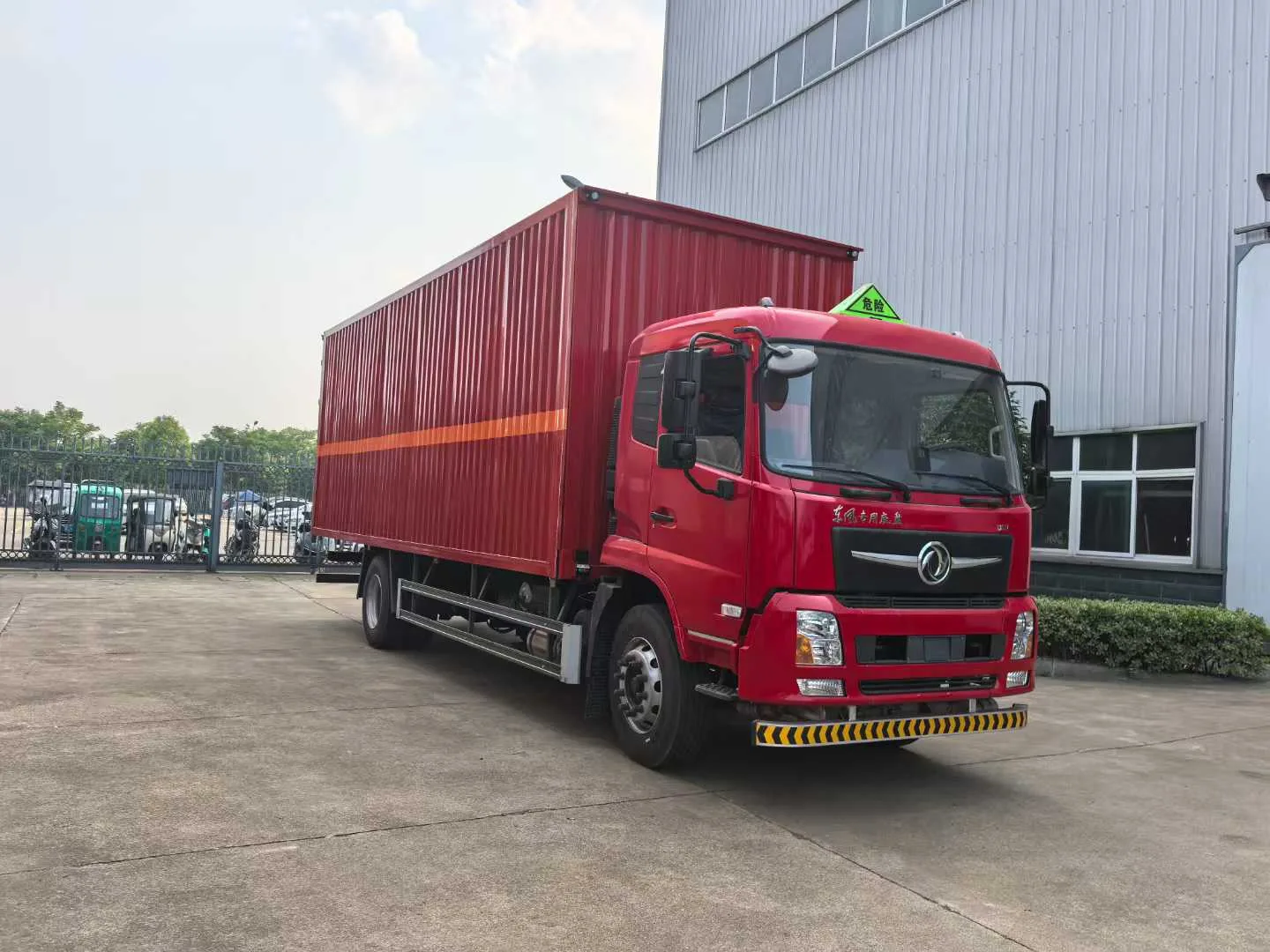 东风D3V厢式危险品运输车 右前45度实拍 红色瓦楞板厢体闭合状态+橙色反光带+危险品顶灯