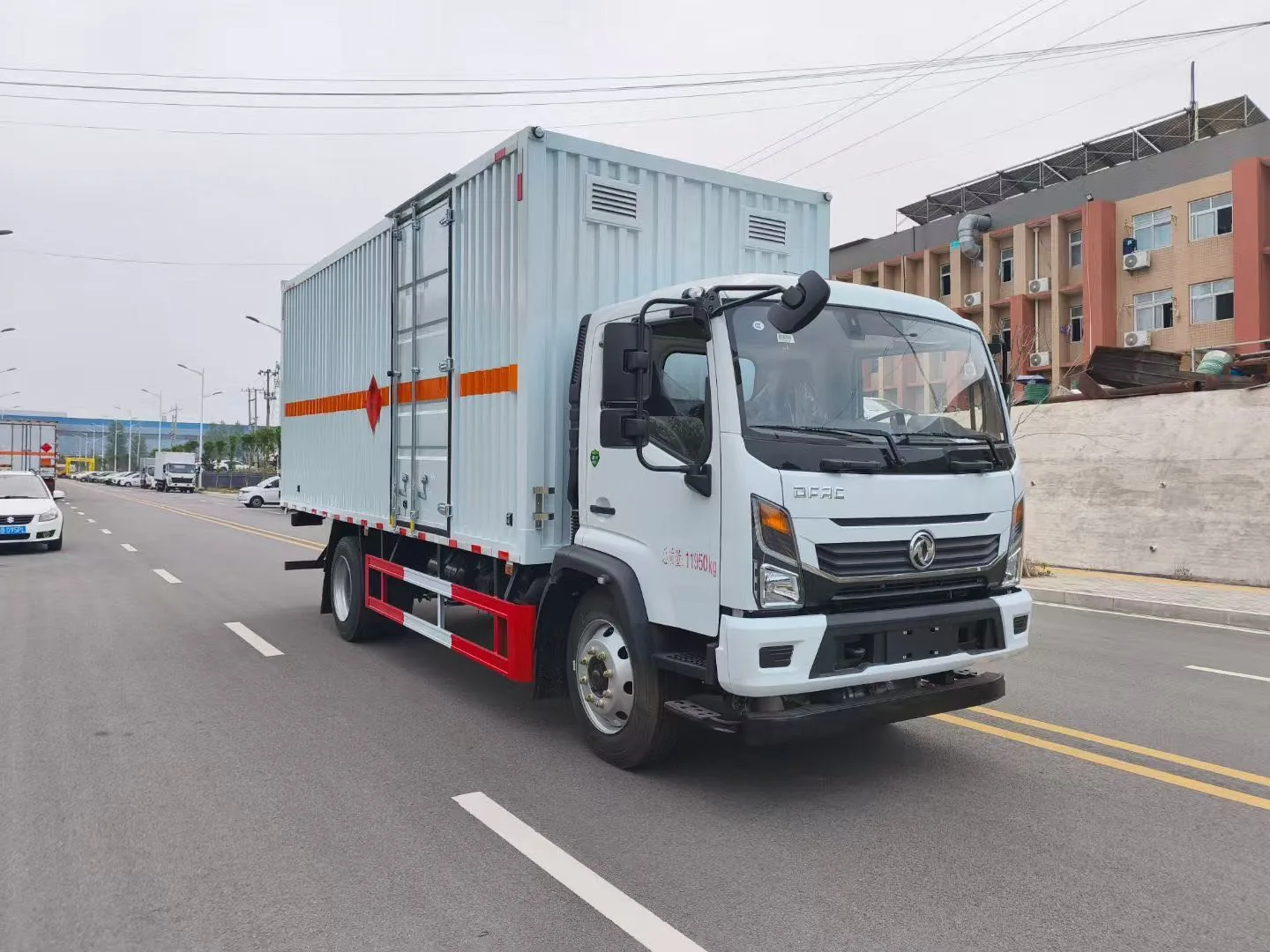 东风凯普特黄牌危化厢式车 右前45度行驶实拍：瓦楞结构厢体（右侧单开侧门）+ 橙色反光带 + 红色菱形标志 + 总质量11950kg