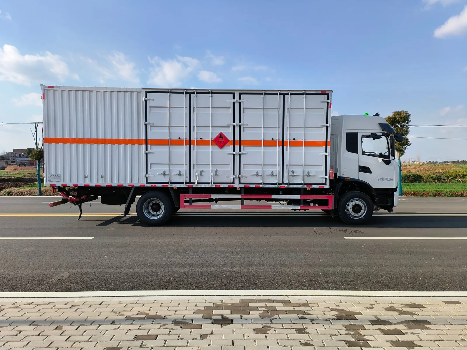 东风天锦KR单桥危险品厢式运输车 平顶驾驶室整车左正侧实拍，瓦楞板白色厢体带橙色反光带与9类菱形标识