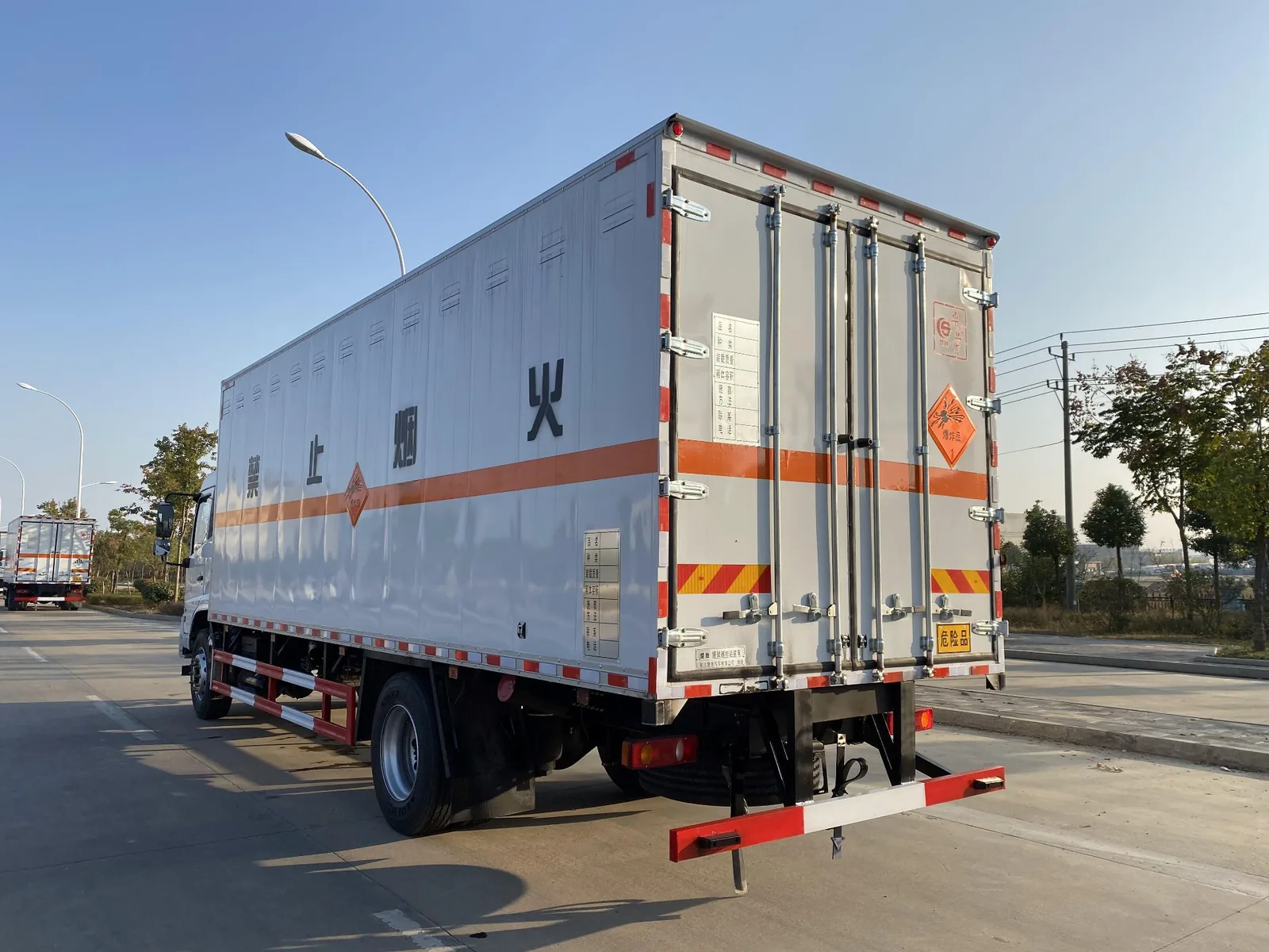 东风天锦单桥6米8爆破器材运输车 右后 45 度实拍，后部对开门热镀锌门杆与合页、爆炸品菱形标识、尾部「危险品」尾牌与防撞杠
