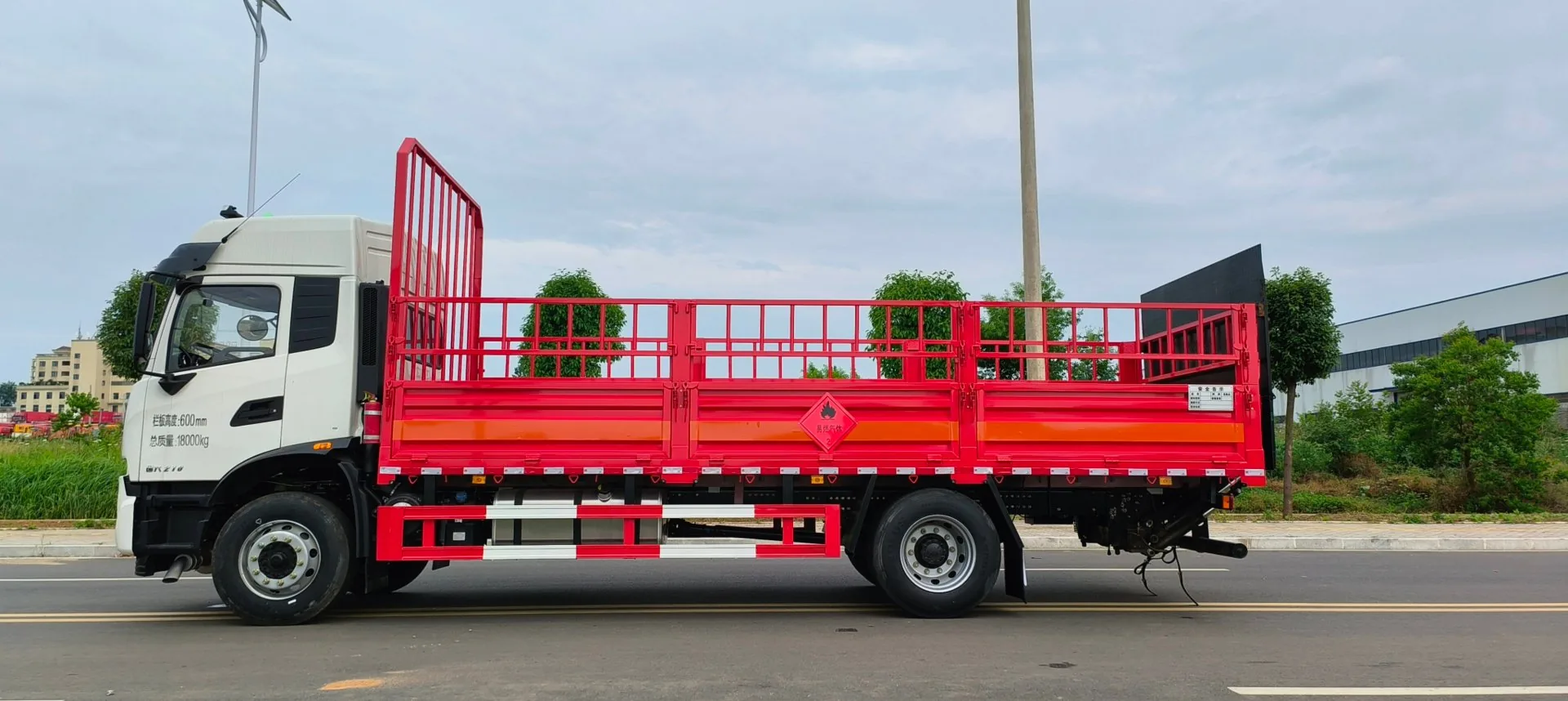 东风天锦KR 6.8米高栏危险品运输车 右侧正侧面实拍：橙色栏板 + 红色仓栅 + 菱形危险品标志 + 侧防护栏 + 尾部液压尾板