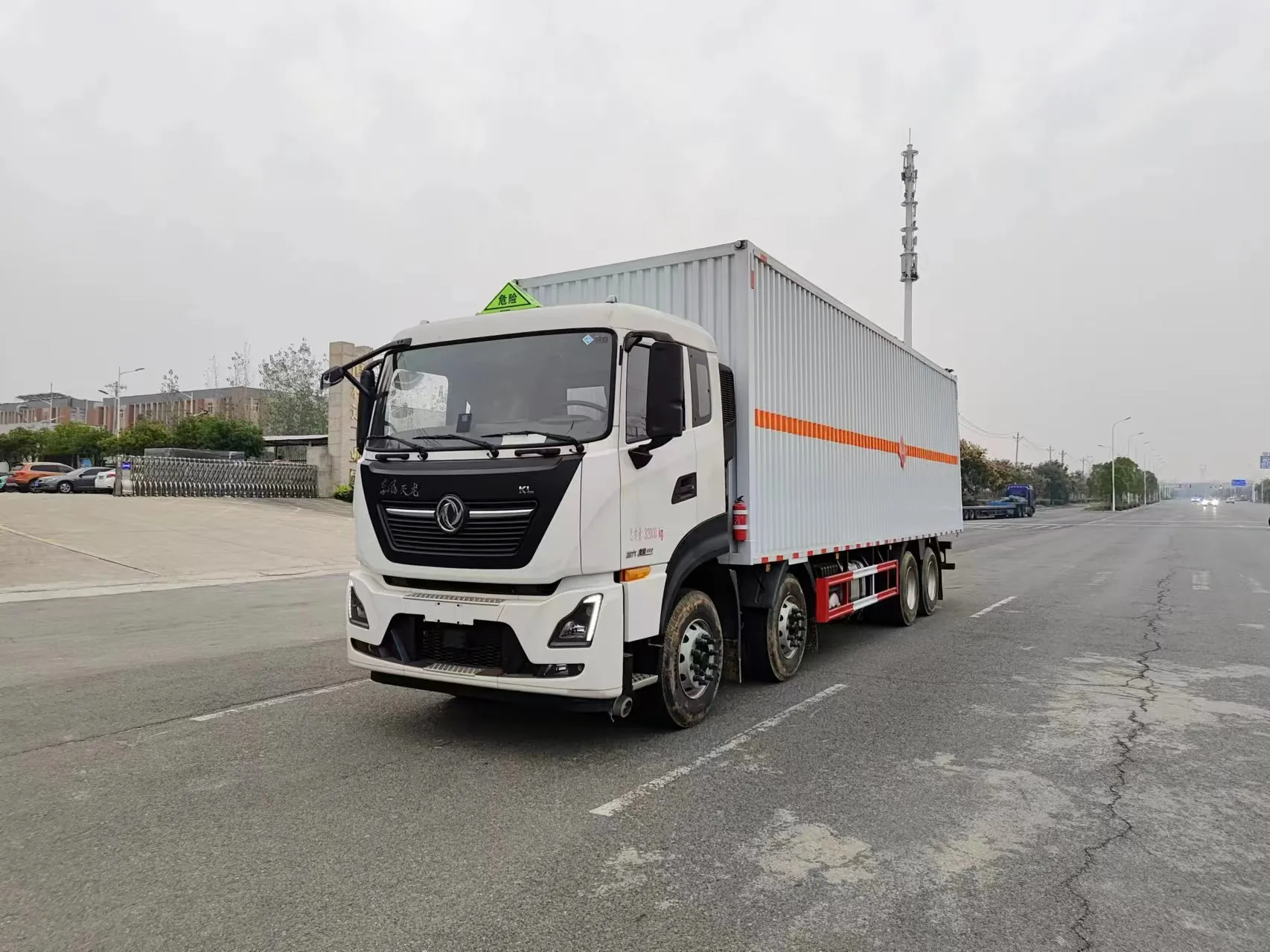 东风天龙KL 9.6米危险品厢式运输车 左前45度实拍：白色瓦楞复合厢体 + 橙色反光带 + 危险品顶灯