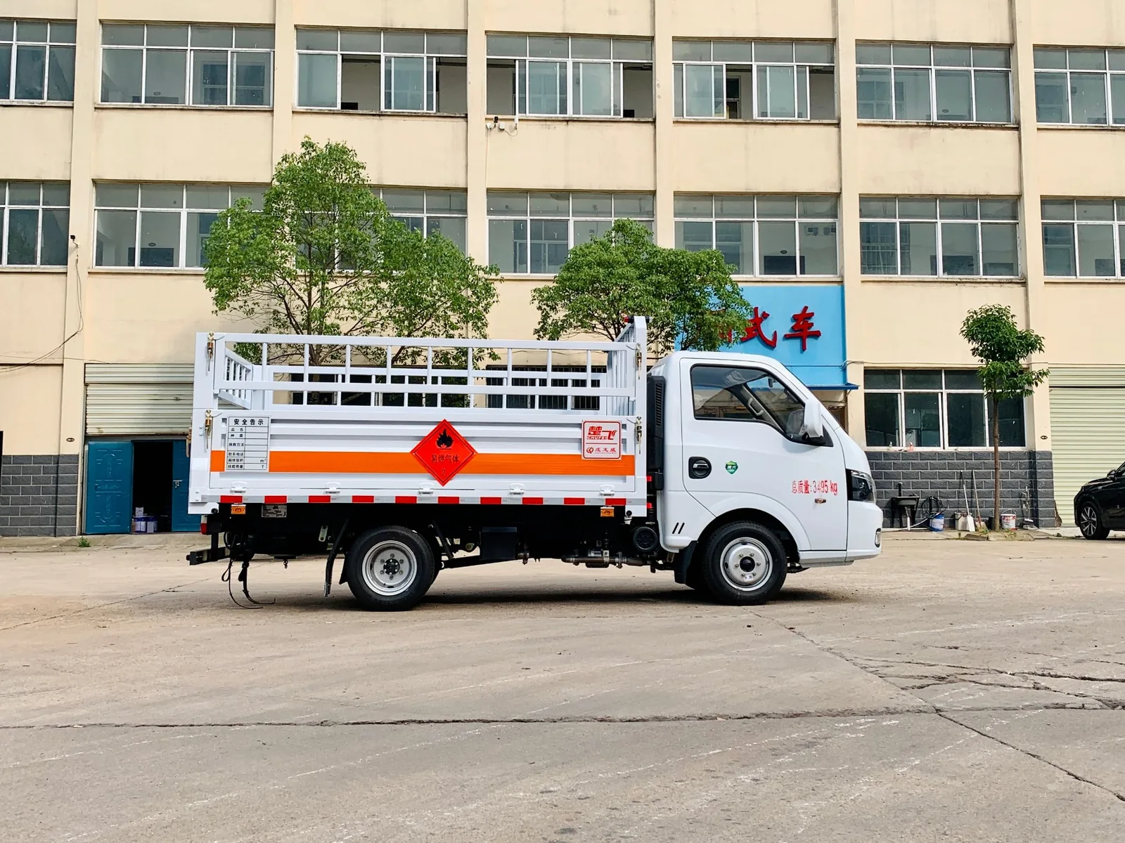 东风途逸汽油版高栏板气瓶运输车 左侧正侧实拍，厂区建筑前高栏板车身与危险品标识