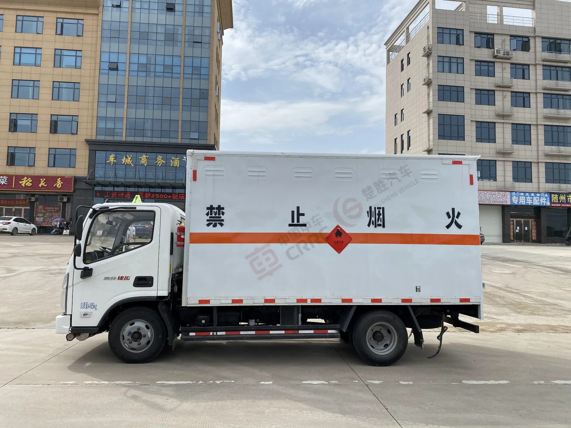 楚胜牌 福田奥铃蓝牌易燃气体厢式运输车，左正侧视角，厢体「禁烟火」四个大字与橙色反光带、易燃气体菱形标识清晰可见，背景为商贸城建筑（标注「总质量 4495kg」牌照信息在驾驶室门下方）