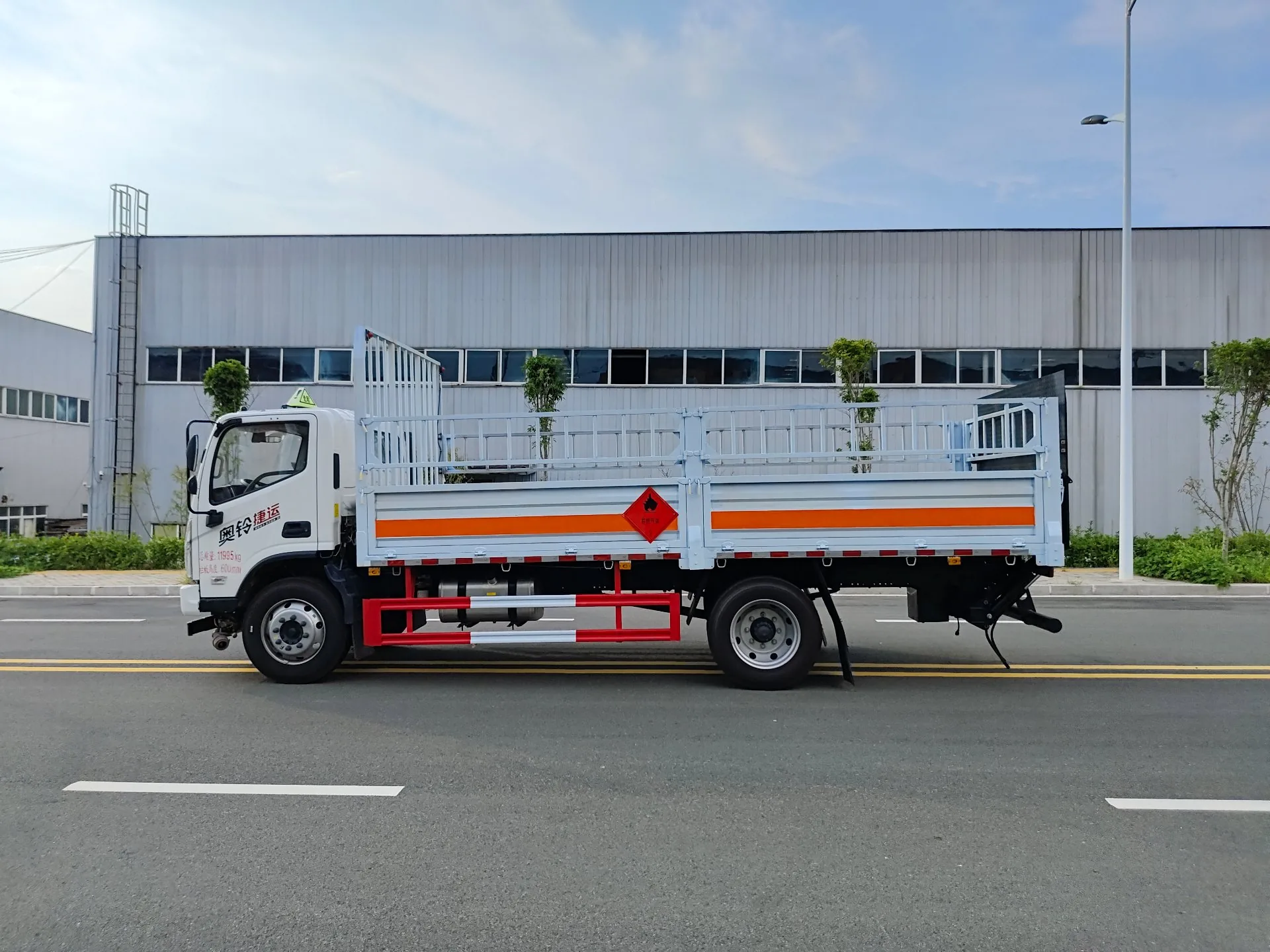  福田奥铃黄牌 5120 气瓶运输车，右正侧视角，驾驶室带「奥铃速运」字样 + 红色栏板 + 易燃气体菱形标识 + 橙色反光带 + 加强型后板簧 + 龙门架圆管结构，厂区外背景