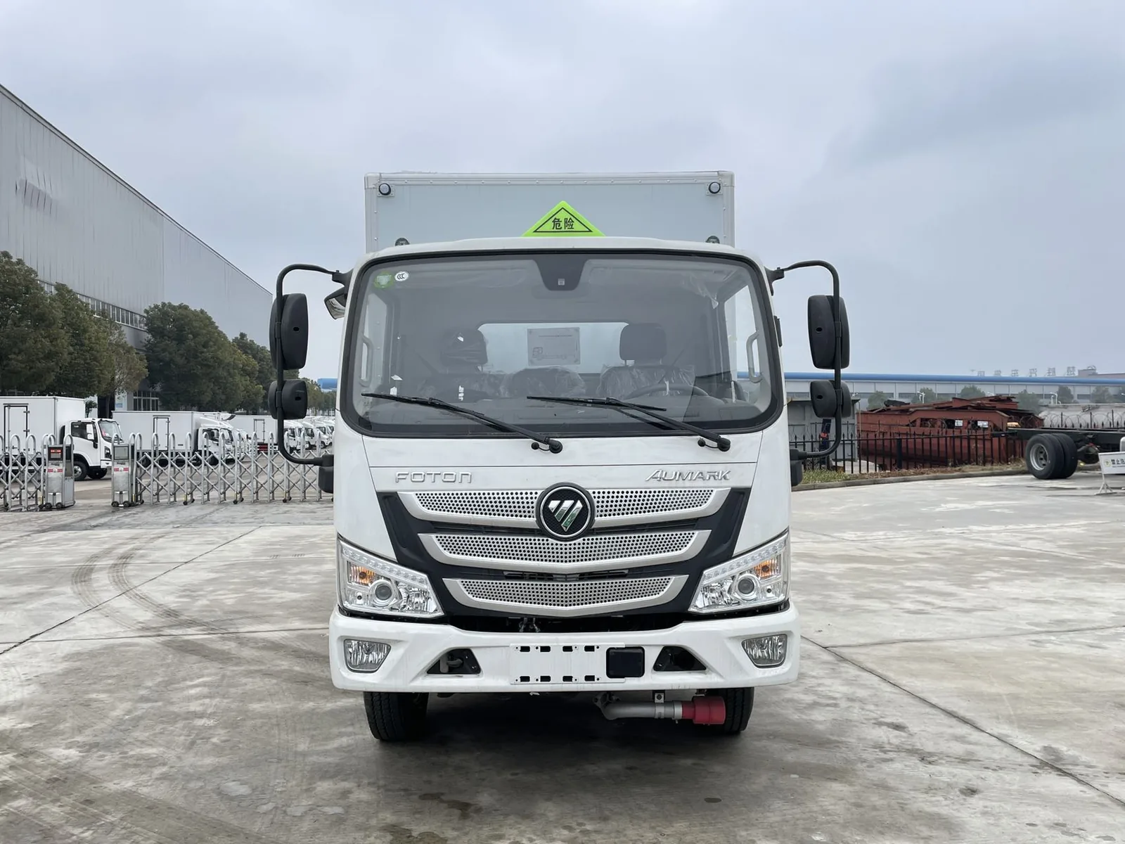 福田欧马可蓝牌爆破器材运输车 车头正视图，白色驾驶室配 FOTON AUMARK 标志与圆形车标，前挡风带「危险」三角顶灯与厂区外场景