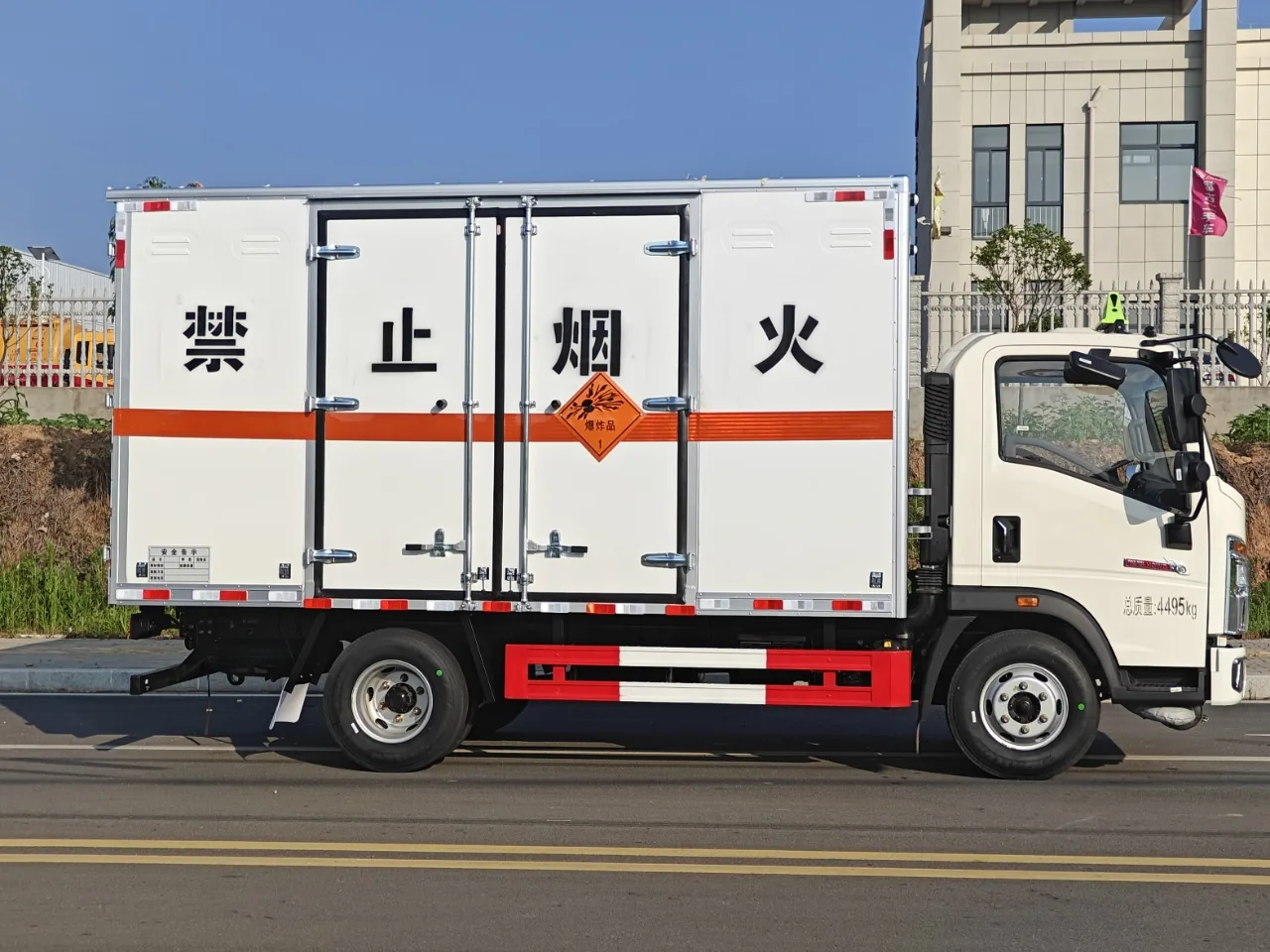 重汽豪沃蓝牌危险品厢式运输车 整车左正侧实拍，厢体带「禁止烟火」四个大字与橙色反光带，厂区外场景