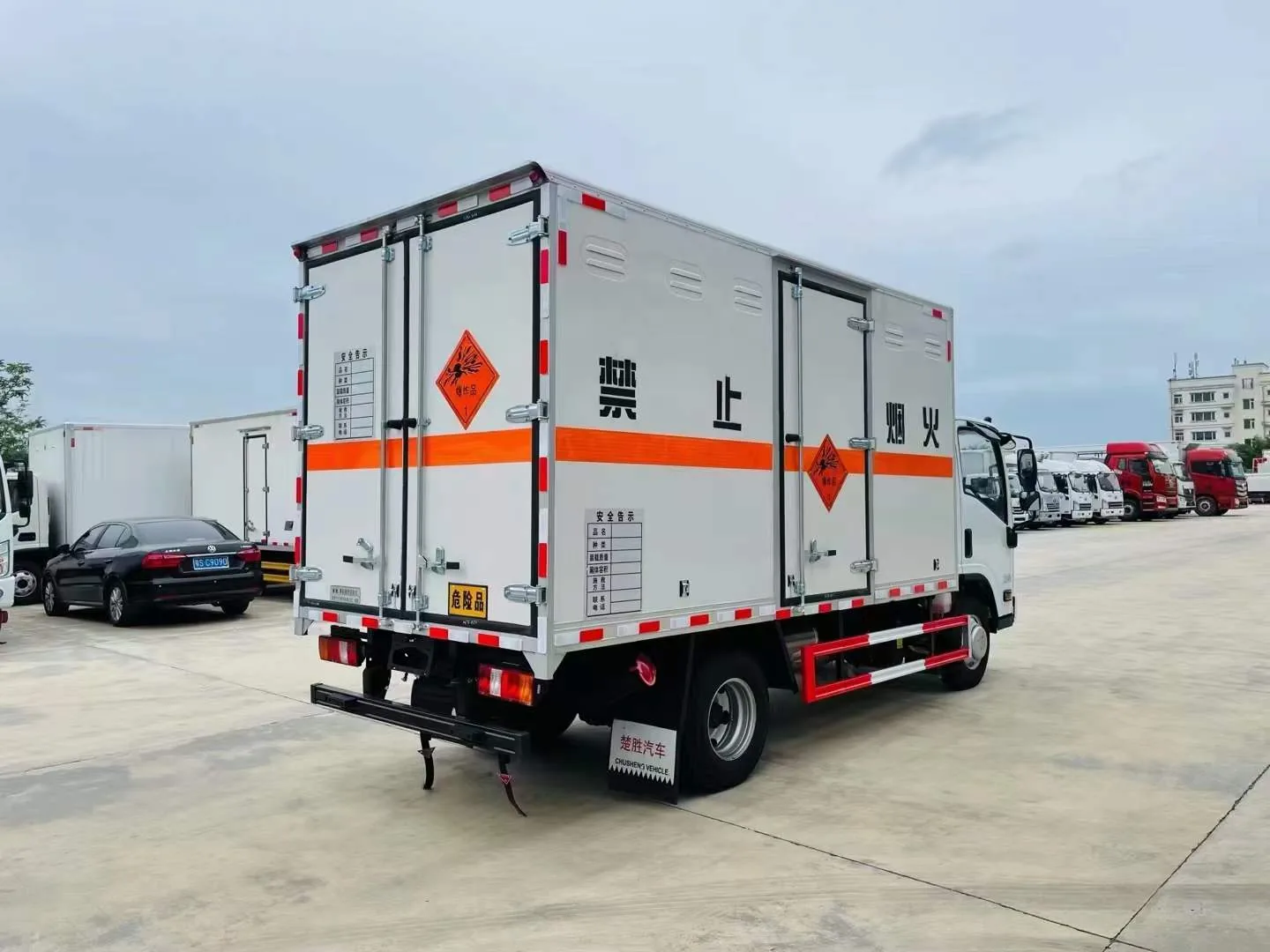江西五十铃蓝牌爆破器材运输车 整车左后 45 度实拍：白色复合板厢体 + 橙色反光腰线 + 1 类爆破器材菱形危险品标识 + 禁止烟火标志 + 危险品告示牌（介质 / UN / 安全告示）+ 后部对开门 + 拖地静电带 + 红色防撞护栏
