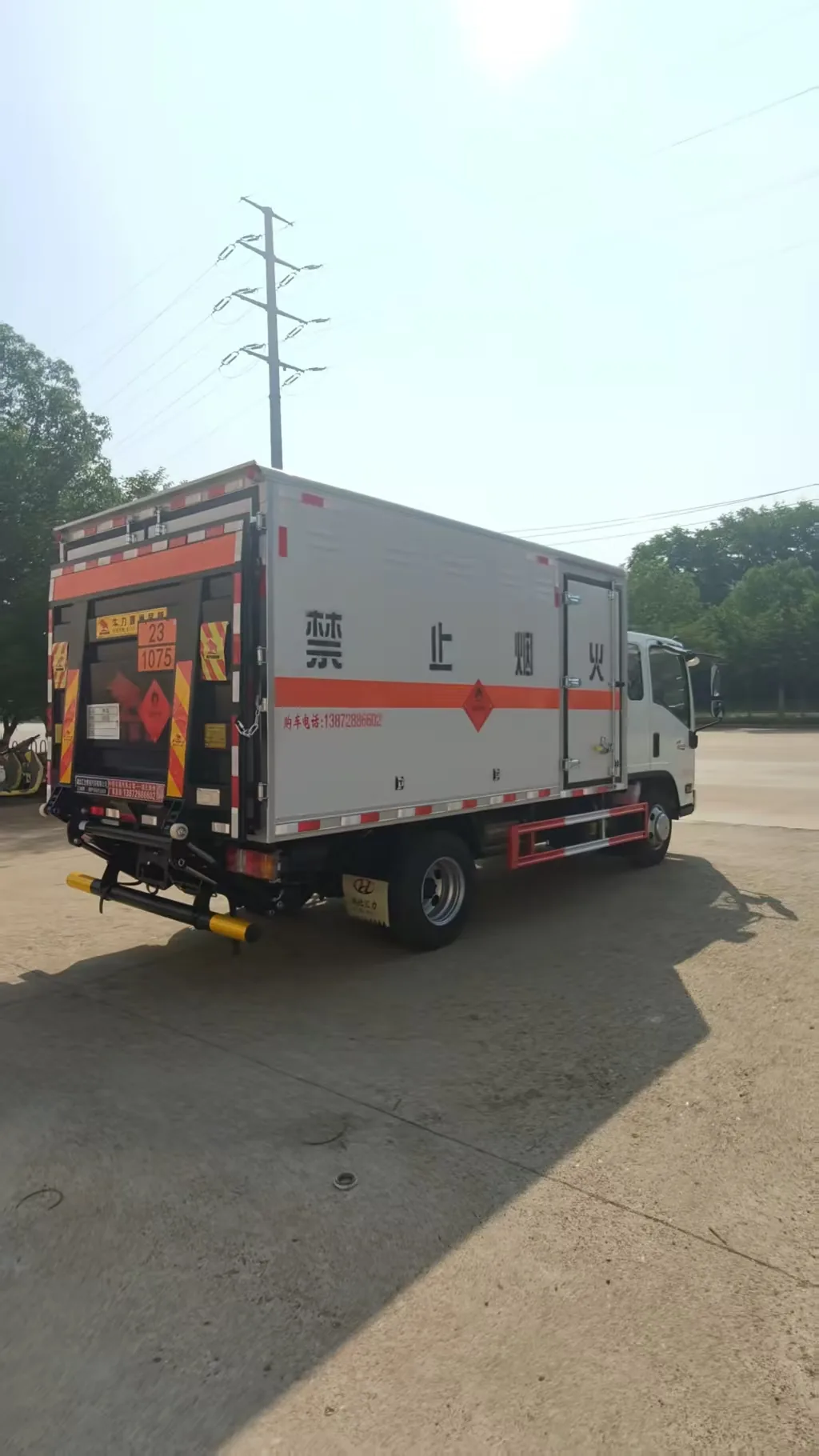 江西五十铃蓝牌危险品厢式运输车实拍，左后 45 度视角，车尾选装液压尾板（尾板铭牌 + 黄色警示标识）+ 厢体「禁止烟火」字样 + 橙色反光带 + 侧门，竖幅构图