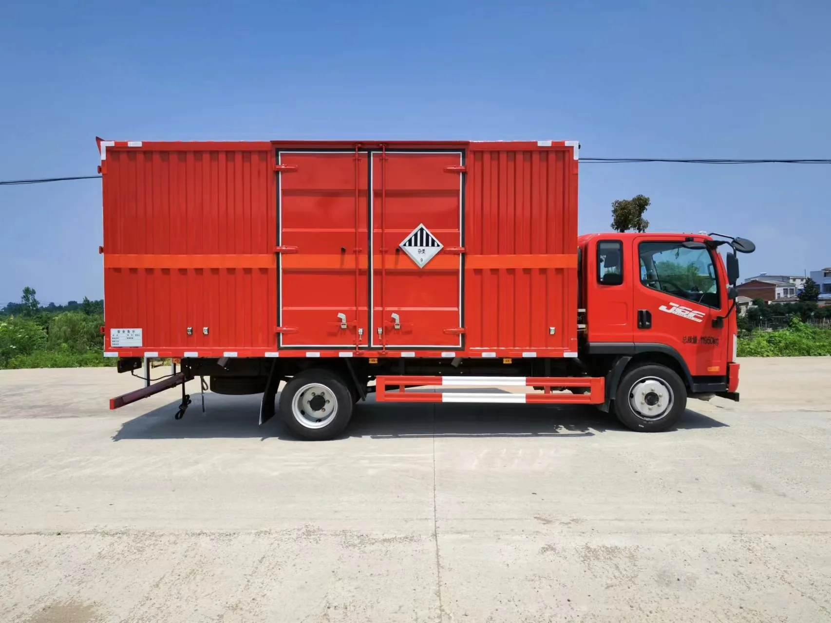 解放J6F黄牌5米2厢长危化品厢式运输车 红色厢体整车正侧面实拍：解放同款驾驶室 + 红色瓦楞厢体 + 红色反光腰线 + 黄色菱形腐蚀品标识