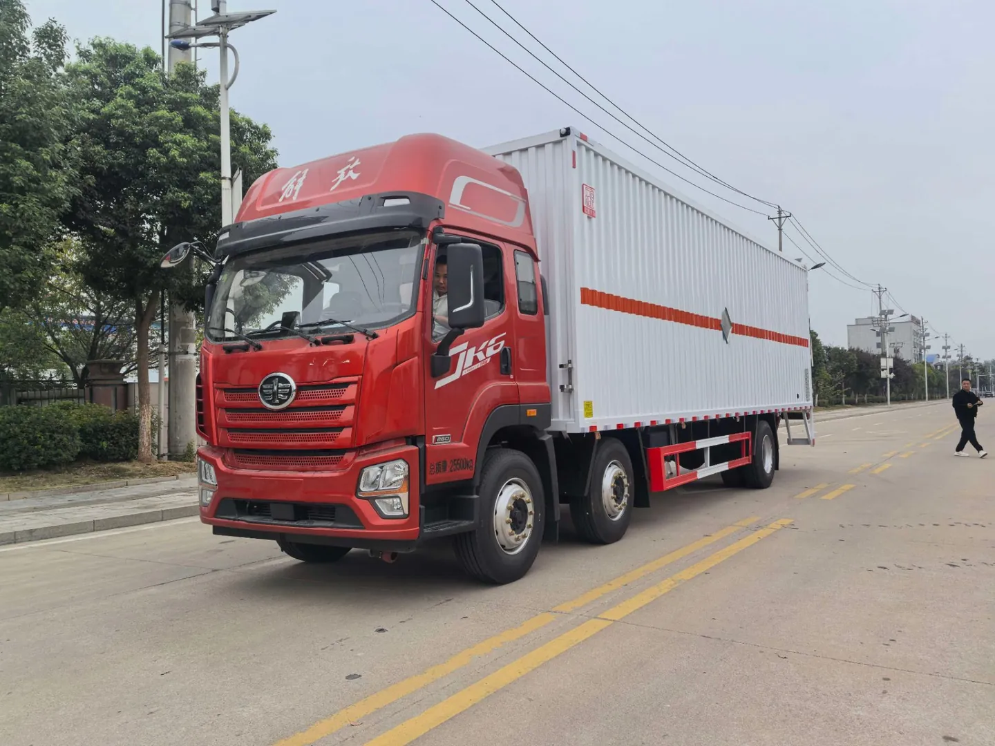 白色厢体整车左前侧实拍：JK6红头驾驶室 + 白色瓦楞厢体 + 危险品标识，户外公路背景
