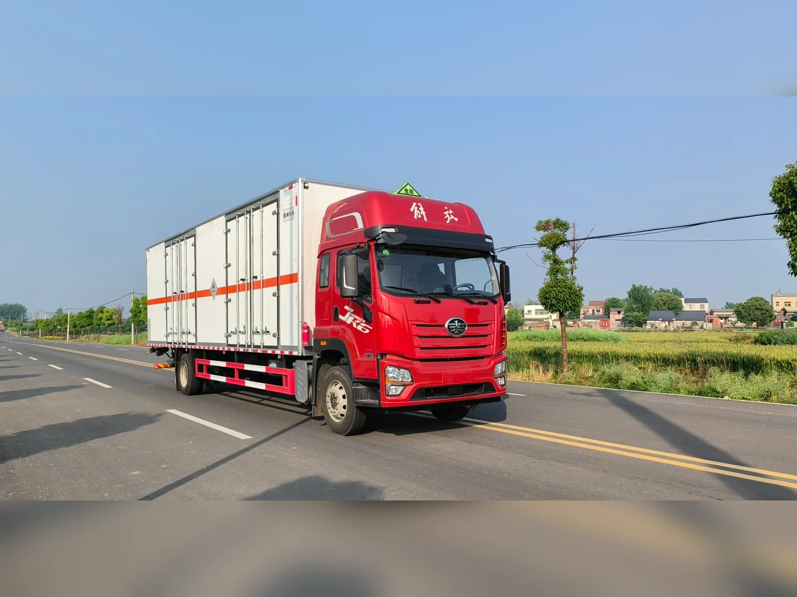 解放JK6单桥危险品厢式运输车 白色平板厢体款式 右前45度行驶实拍：白色厢体带侧开门 + 橙色反光条 + JK6红色驾驶室 + 危险品顶灯