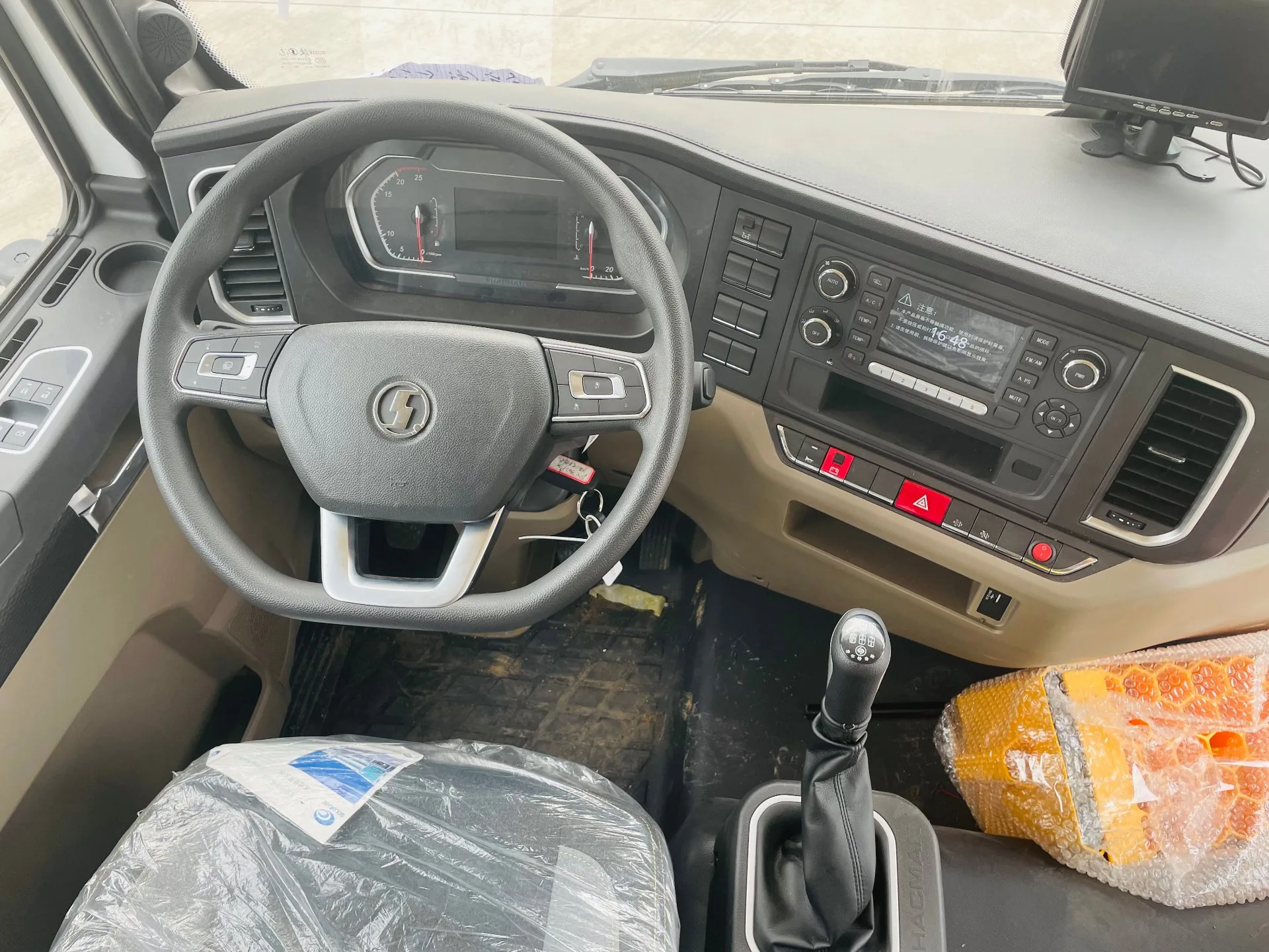 陕汽德龙L5000 爆破器材运输车 驾驶室内部，多功能方向盘、仪表盘、中控多媒体屏与机械挡杆